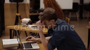 图书馆使用笔记本电脑的专注年轻人侧视图。英俊的欧洲留学生